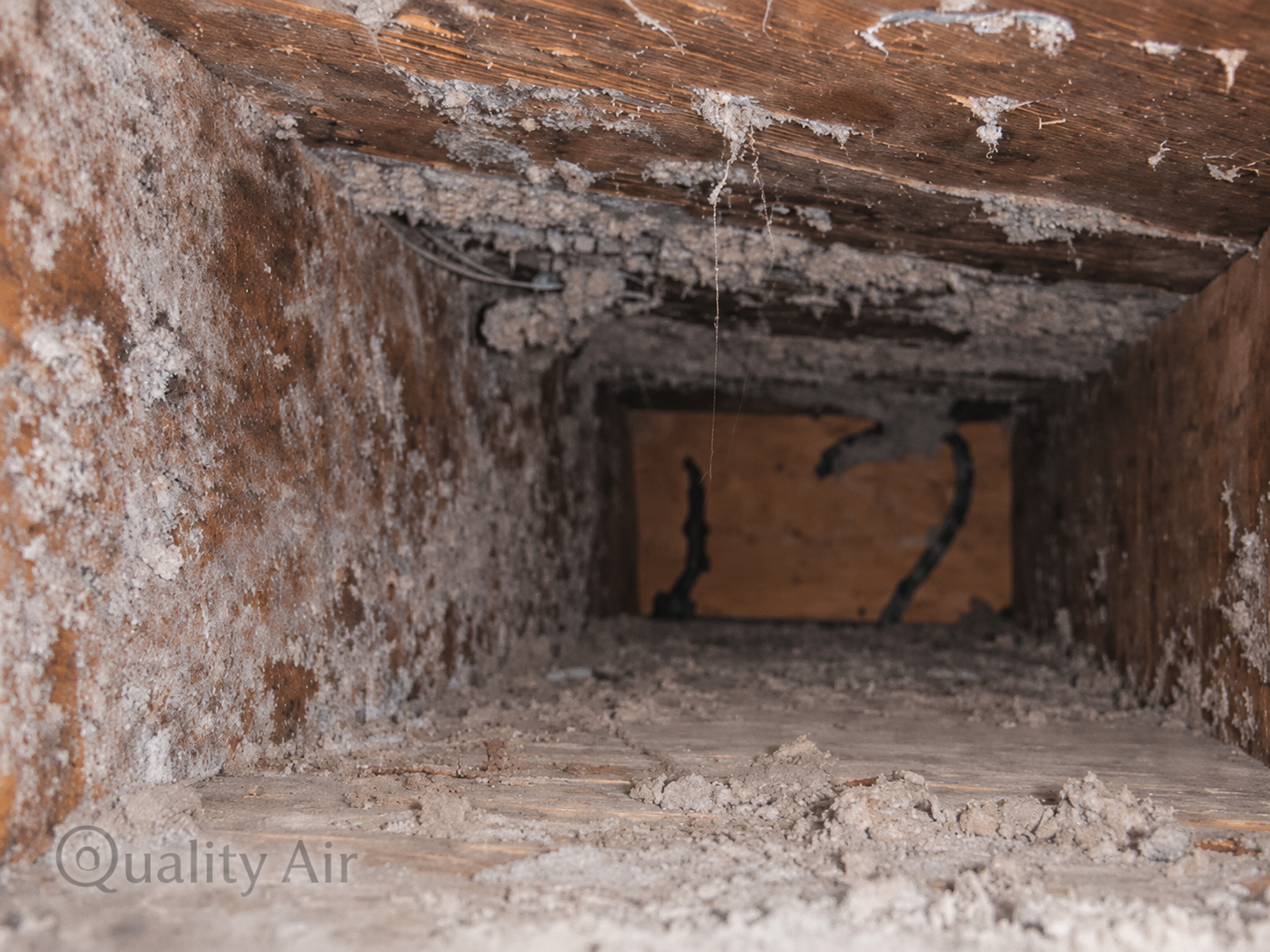 Interior of an air duct before cleaning showing thick layers of dust, debris, and contaminant buildup left by a previous inadequate cleaning