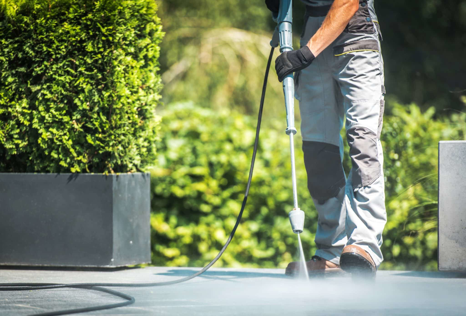 High-pressure washing restoring residential driveway to clean original condition in Hamilton